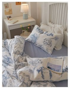 an unmade bed with blue and white comforter, pillows and a book on it