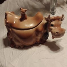 a ceramic cow on a table next to a vase with two small animals in it