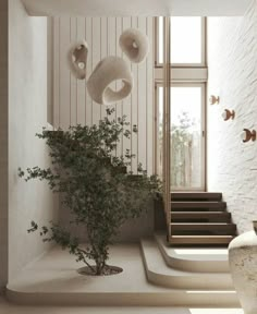 there is a potted plant next to the stairs in this modern house with white walls and flooring