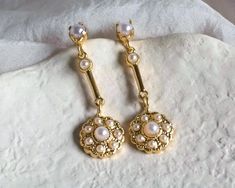 Discover the charm of our exquisite bridal earrings, featuring a delicate blend of gold and baroque pearls. These small yet elegant dangling studs are designed to complement your bridal ensemble with a touch of refined luxury. Crafted with care, these earrings offer a subtle glow that enhances your natural beauty without overpowering it. The combination of gold and baroque pearls brings a timeless elegance to your look, making them perfect for the bride who appreciates understated sophistication. Whether you're walking down the aisle or celebrating at a special event, these earrings are designed to add a gentle, sophisticated sparkle to your attire. Their classic design and delicate detailing make them a beautiful choice for any bride who desires a touch of grace and elegance. Celebrate yo Elegant Yellow Gold Pearl Earrings For Wedding, Delicate Yellow Gold Bridal Earrings With Pearl Drop, Vintage Gold Pearl Earrings For Wedding, Victorian Pearl Earrings For Wedding, Gold Pearl Embellished Earrings For Wedding, Yellow Gold Pearl Charm Bridal Earrings, Gold Pearl Charm Earrings For Wedding, Wedding Yellow Gold Pearl Charm Bridal Earrings, Dainty Wedding Pearl Earrings With Pendant