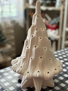 a white ceramic christmas tree sitting on top of a checkered tablecloth covered table