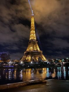 the eiffel tower lit up at night with lights reflecting in the water below