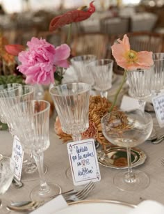 there are many wine glasses on the table with place cards in front of each one