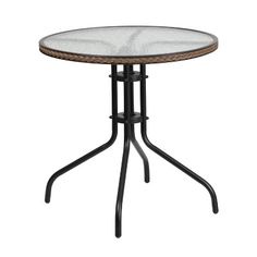 an outdoor table with glass top and wrought iron base, on a white backdrop background