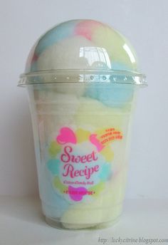 a plastic cup filled with ice cream on top of a white table next to a wall