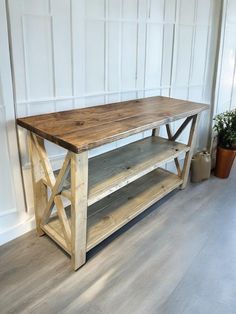 a wooden table sitting on top of a hard wood floor next to a potted plant