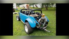 an old blue car is parked in the grass with its hood up and engine out