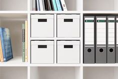 a white bookcase filled with lots of books and binders next to a stack of folders