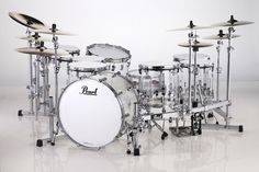 a white drum set sitting on top of a white floor next to a pair of drums