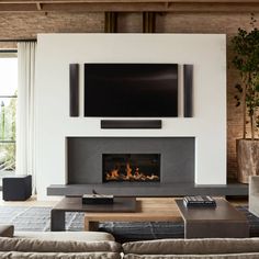 a living room with couches and a television mounted on the wall over a fireplace