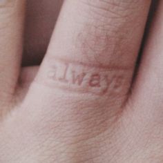 a close up of a person's hand with a small tattoo on their finger