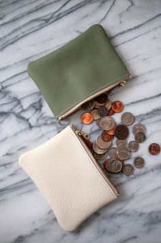 two purses with coins in them on a marble surface