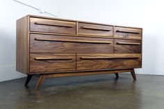 a large wooden dresser sitting on top of a cement floor next to a white wall