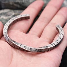 a person is holding a silver bracelet with roman numerals on it's side