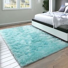 a bedroom with a large bed and blue rugs on the wooden floor next to it