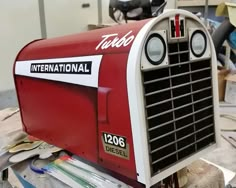 a red and white mailbox sitting on top of a table next to other items