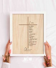 two hands holding up a framed wooden cross