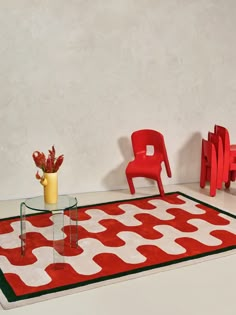 a red chair sitting next to a table on top of a rug