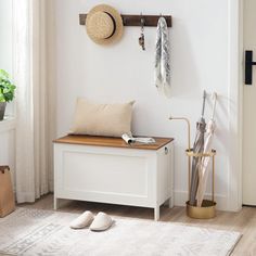 a white bench sitting in front of a window next to a wooden shelf with hats on it