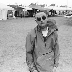 a man with sunglasses and a hat on standing in the middle of an open field