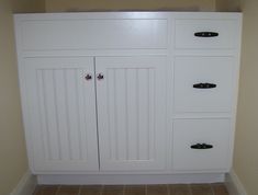 an empty bathroom with white cabinets and tile flooring