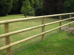 a wooden fence in the middle of a grassy field