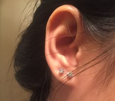 a close up of a person's ear with two diamond studs on it