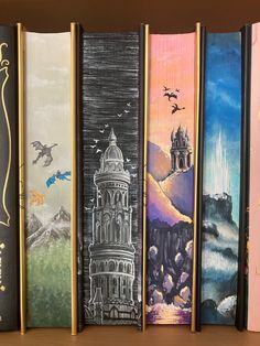 four books are lined up on a shelf with pictures painted on the covers and in front of them