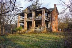 an old abandoned house sitting in the middle of a forest with no leaves on it