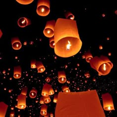 many lit up lanterns floating in the air