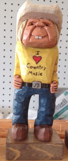 a ceramic statue of a man wearing a yellow shirt and jeans with the words i love country music on it