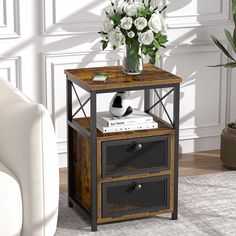 a vase with white flowers on top of a wooden side table next to a couch