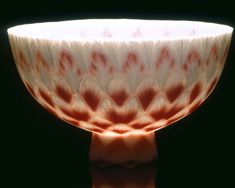 a white and red bowl sitting on top of a wooden table next to a black background