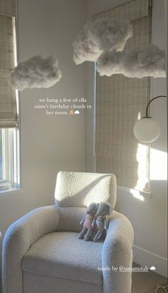 a chair with stuffed animals sitting on it in front of clouds hanging from the ceiling