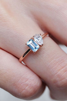 a close up of a person's hand wearing a ring with an aqua blue topazte