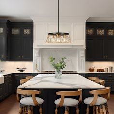 a large kitchen with black cabinets and white counter tops, an island in the center