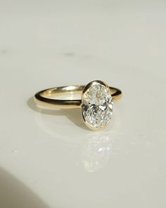 a yellow gold ring with a single diamond in the center on a white table top