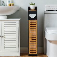 a white toilet sitting next to a sink and a wooden shelf with towels on it