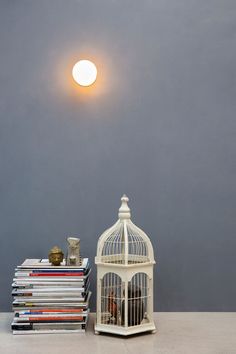 a white birdcage sitting on top of a table next to a stack of books