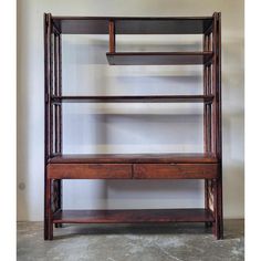 a wooden shelf with drawers and shelves on the top, in front of a white wall