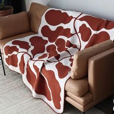 a couch with a blanket on top of it in front of a chair and potted plant