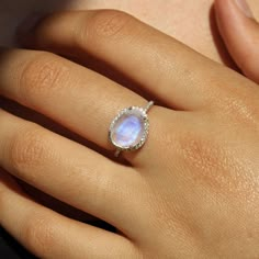 Introducing the Skye Moonstone Ring—a classic piece that features a genuine Rainbow Moonstone, beautifully framed by a halo of sparkling crystals on a pave band. Choose between luxurious 14k Gold Vermeil or elegant Sterling Silver, and let this naturally stunning gemstone captivate you with its unique charm. Each Rainbow Moonstone is handpicked for its individual beauty, ensuring that your ring is truly one-of-a-kind. Details:Gemstone: 9x11mm Genuine Rainbow MoonstoneRing Face (including crystal Cheap Oval Crystal Ring, Elven Accessories, Gold Moonstone Ring, Pave Band, Rainbow Moonstone Ring, Rhinestone Bridal, Vermeil Jewelry, Moonstone Jewelry, Pretty Rings