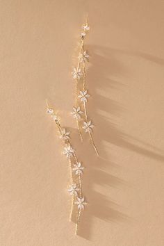 two pairs of gold and white flower hair pins on top of a beige surface with shadows