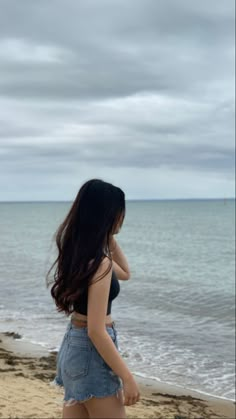 a woman standing on top of a beach next to the ocean