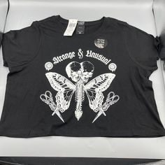 Cosmic Aura Strange & Unusual Glow-In-The-Dark Crop T-Shirt Small Something Strange And Unusual Is Fluttering Into Your Wardrobe! Turns Some Heads With This Tee, Featuring A Butterfly Creature With A Spinal Center And Two Skulls, Plus "Strange & Unusual" In A Gothic Font Up Top. Wander Into The Dark To Watch This Tee Glow! * 100% Cotton * Wash Cold; Dry Low * Length: 17" * Glows In The Dark * Imported Edgy Fitted T-shirt For Music Festival, Edgy Halloween Graphic Print Tops, Fitted Trendy T-shirt With Skull Print, Black Skull Print Band Merch Tops, Skull Print Graphic Tee For Alternative Fashion, Halloween Graphic Tee For Concert, Black Halloween Crop Top For Streetwear, Graphic Tee Tops With Skull Print For Alternative Fashion, Black Punk Top With Front Print