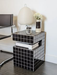 two black and white side tables with flowers on each one, next to a chair