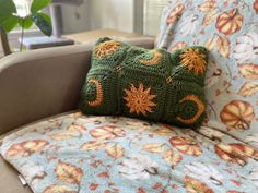 a green crocheted pillow sitting on top of a couch next to a plant