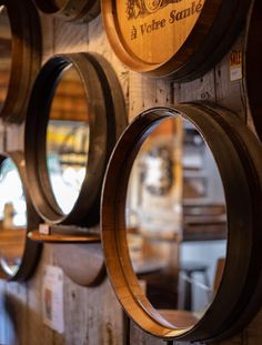 several wine barrels are hanging on the wall with their lids open and there is a mirror in front of them