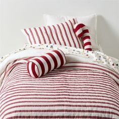 a red and white striped bed spread with two pillows on top of it, next to a pillow case