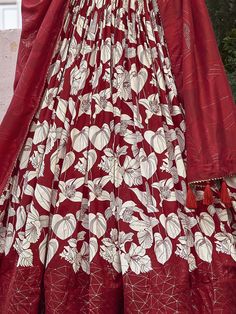 The red color tussar silk lehenga with floral and foil print work is a captivating ensemble that embodies both tradition and modernity. This semi-stitched lehenga, designed to fit up to 42 inches, boasts a luxurious 3.80-meter flair, providing a dramatic and elegant silhouette. The 42-inch length ensures the lehenga drapes beautifully, creating a striking visual impact. Accompanied by an unstitched choli with 0.80-meter material, this outfit allows for a tailored fit, enhancing both comfort and Red Raw Silk Anarkali Set, Red Raw Silk Anarkali Set With Straight Kurta, Red Raw Silk Anarkali Set For Eid, Eid Festive Choli With Printed Motifs, Festive Eid Choli With Printed Motifs, Red Raw Silk Anarkali Set With Dupatta, Red Unstitched Chanderi Anarkali Set, Festive Silk Sharara With Floral Print, Traditional Sharara With Printed Motifs For Wedding